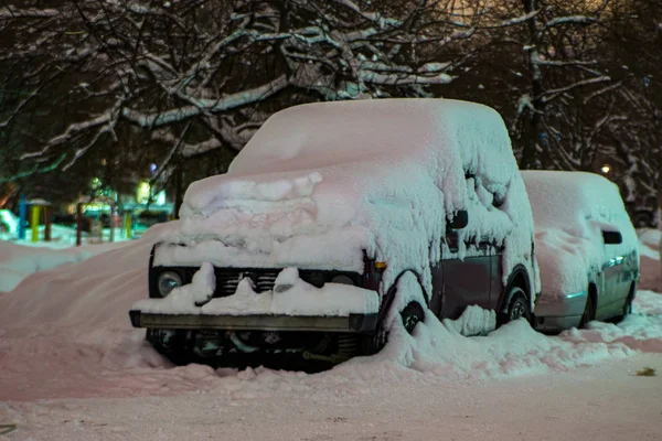 Na dziedzińcu budynku mieszkalnego pod śniegiem znajduje się stary, terenowy samochód pasażerski. — Zdjęcie stockowe