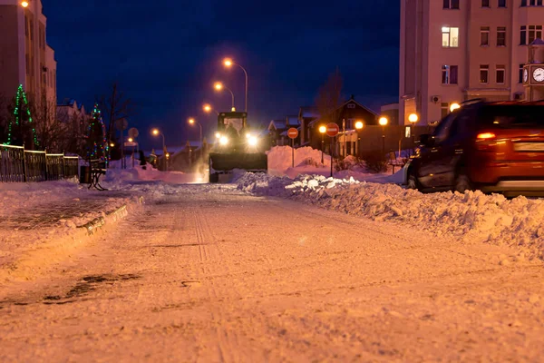 Usuwanie śniegu z ulic nocnego miasta przy użyciu ciężkiego sprzętu drogowego — Zdjęcie stockowe