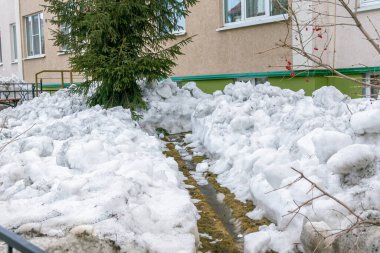 Eriyen suyu temelden kaldıran oluklar ve baharda binanın güneşlikleri kardan temizleniyor.