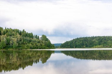 Büyük göl bulutlu havada taygayla çevrilidir.