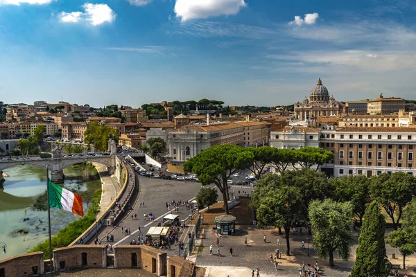 イタリアの旗の上にあるサンタンジェロ城からの美しい景色、観光客が歩くと、バックグラウンドでティバー川とバチカン。ローマの美しい晴れた天気、おとぎ話はローマのように見えます。ローマの観光地-サンタンジェロ城 — ストック写真