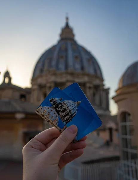 Dívka drží dva lístky do kupole baziliky svatého Petra z Vatikánu před kupolí. Zaměření na lístky, rozmazané pozadí — Stock fotografie