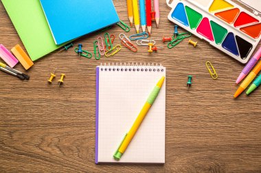 Ahşap zemin üzerinde bir sürü kırtasiye eşyası olan bir sanatçının masası, üst görünüm