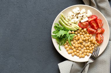 Baharatlı nohut, avokado, domates, arka planda aragula kasesi, üst manzara. Lezzetli dengeli gıda konsepti, kopyalama alanı