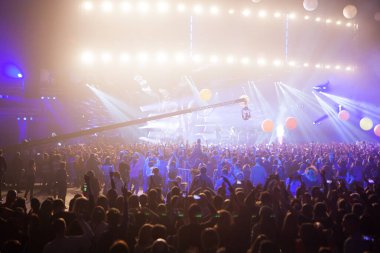 Parlak sahne ışıkları önünde rock konserinin siluetleri.