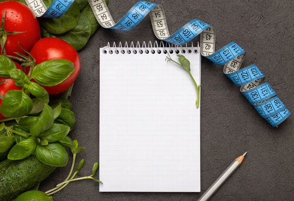 Diyet konsepti ve sağlıklı yiyecekler, fotokopi alanı olan not defteri, karanlık arka planda sebzeler, üst manzara..