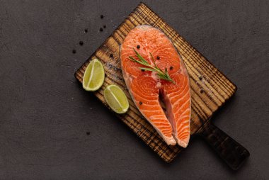 Siyah arka planda çiğ somon bifteği. Koyu masada taze kırmızı balık, boşluğu kopyala