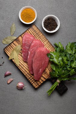 Sağlıklı yemek pişirmek için malzemeli çiğ et bifteği, siyah arka planda tahta kesmek.