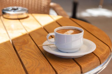 Ahşap bir masada bir fincan cappuccino kahve. Yaz. Günaydın..