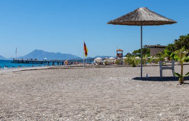 08-12-2019. Kemer, Türkiye. Sazlığın gölgesinde beyaz plastik sandalye. Şehir plajı. Akdeniz.