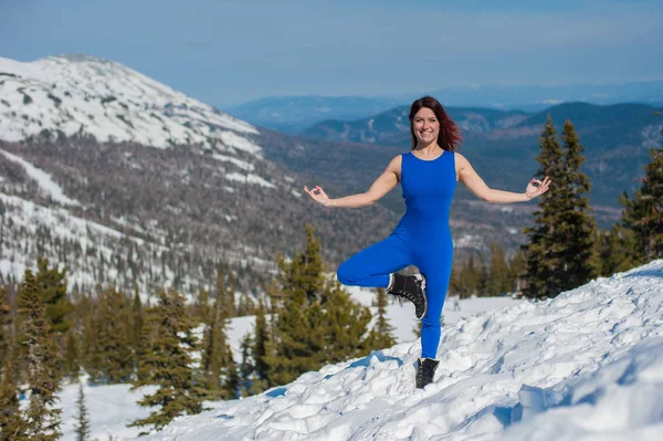 A garota na roupa azul fazendo ioga no topo de uma montanha — Fotografia de Stock