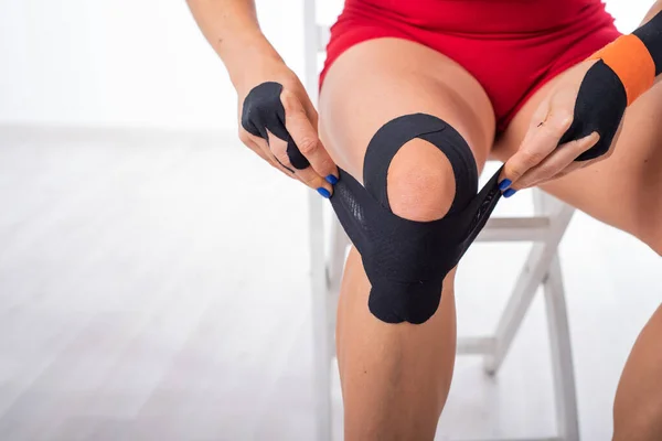 L'athlète met une cassette médicale sur son genou. Traitement alternatif des lésions articulaires et tendineuses. Physiothérapie de l'inflammation chronique des articulations de la jambe féminine . — Photo