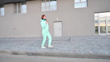Nane aromalı ve eşarplı bir kadın sokakta yürüyor ve dans ediyor. Mavi kazaklı, pantolonlu ve gözlüklü mutlu kızıl saçlı kız yürüyor ve poposunu sallıyor. Güneşli, güneşli bir sabah.