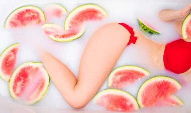 Bir kadın karpuz dilimleriyle süt banyosu yapıyor. Spa cilt bakımı. Kırmızı bikinili kız. Jakuzide olmayı seviyor. Kleopatra Gençleştirme. Yukarıdan bak. Rahatlama. Su tedavileri.