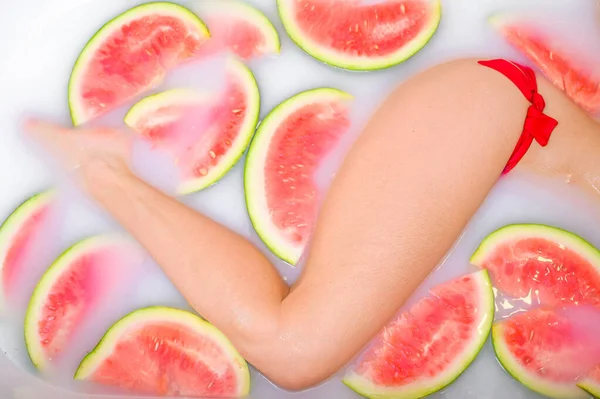 Eine schlanke Frau nimmt ein Milchbad mit Scheiben Wassermelonen. Wellness-Hautpflege-Behandlungen. Mädchen im roten Bikini. gerne im Whirlpool. Cleopatra-Verjüngung. Blick von oben. schöne Beine. — Stockfoto