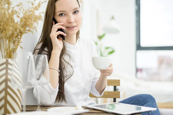 Beyaz gömlekli bir kadın bir kafede kahve içiyor. Öğle yemeği molasında olan bir kadın ofis çalışanı iş sorununu telefonla çözer. Orta seviye yönetici — Stok fotoğraf