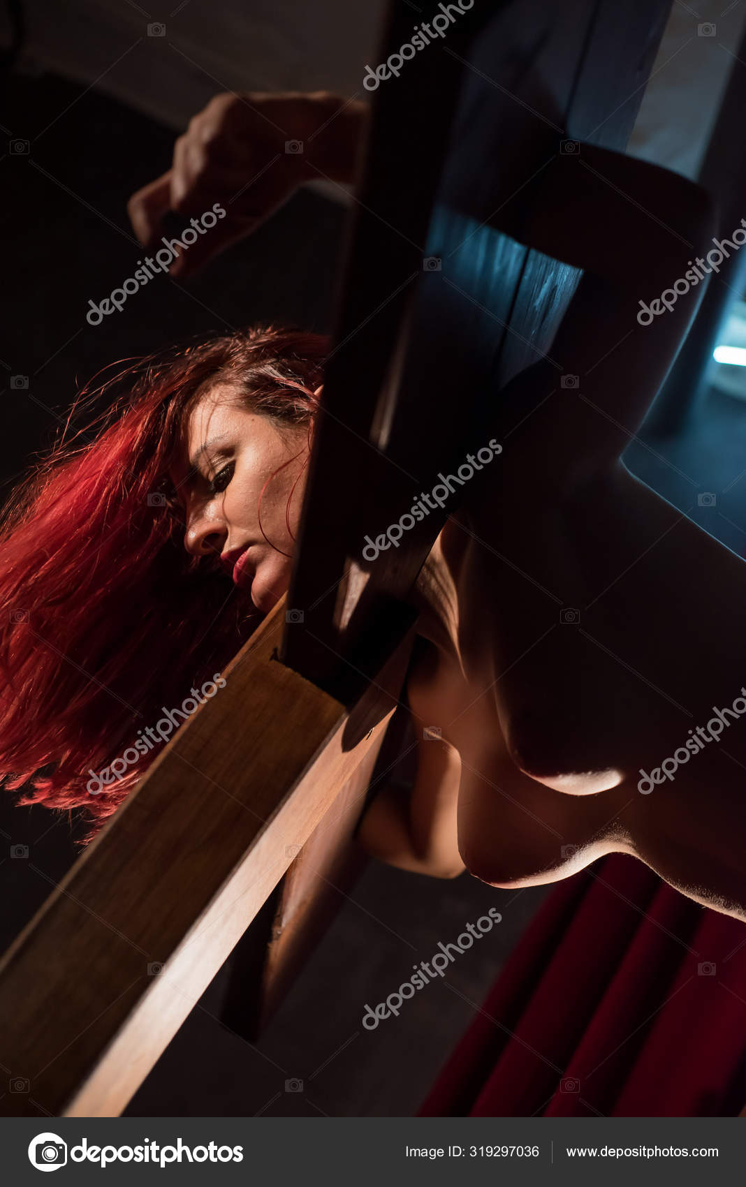 A redhead woman with a naked group is enclosed in a wooden pillory during sexual games. BDSM Erotic fantasies. Subordination pic