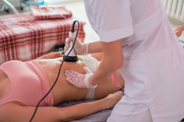 Kadın karın bölgesindeki selüliti, karın masajını kaldırma prosedürü. Kilo vermek için ultrasonik masaj. Cerrahi müdahalede bulunmadan kadın figürünün düzeltilmesi. Karnına yakın çekim..