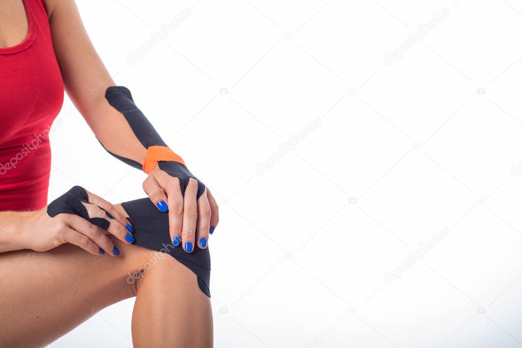 The athlete puts a medical tape on his knee. alternative treatment for joint and tendon injuries. Physiotherapy of chronic inflammation of the joints of the female leg.