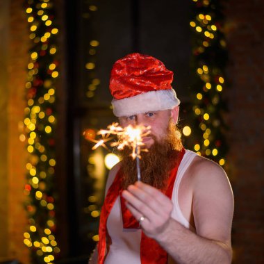 Noel Baba 'nın pırıltıları. Noel Baba şapkalı kızıl sakallı bir adam şaka olsun diye büyüleyici bir fotoğraf çekiyor..