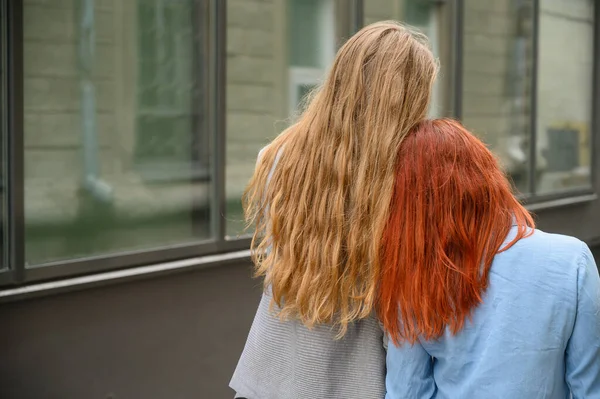 Relaciones del mismo sexo. Una feliz pareja de lesbianas caminaron por la calle y gentilmente se abrazaron alrededor de la cintura. Las espaldas de dos hermosas mujeres en una cita. Dos chicas gay en un paseo . — Foto de Stock