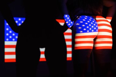 Amerika Birleşik Devletleri bayrağının güzel, büyük bir kadın poposuna yansıtılması. Projektör kadın vücudunda bir bayrak ile parlıyor..