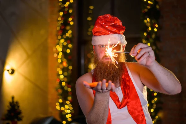 Santa con destellos navideños. Un hombre con barba roja en un sombrero de Papá Noel imita a las mujeres. —  Fotos de Stock