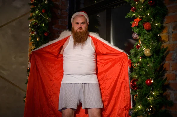 Mauvais Père Noël seul à Noël. Homme agressif dans un costume du Père Noël sur le fond de décorations du Nouvel An . — Photo