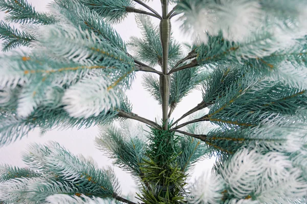 Arbre artificiel écologique pour la nouvelle année. Un arbre de Noël nu sans décorations est debout contre un mur blanc. Traditions pour des vacances en famille habillant une épicéa. Gros plan . — Photo
