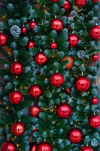 Fundo de uma árvore de Natal decorada com bolas de vidro vermelho e guirlandas leves. Luzes e cones pendurados na árvore de Natal para o Ano Novo . — Fotografia de Stock