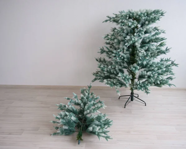 Trozos independientes de árbol de Navidad artificial contra una pared blanca. La instalación del árbol para un nuevo año. Abeto reutilizable compuesto. Decoración para las vacaciones. Protección contra la deforestación . — Foto de Stock