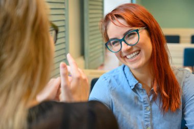 İki kız arkadaş bir kafede oturmuş el ele tutuşuyorlar. Kahve içen, gülümseyen ve flört eden iki kadın. Lgbt.