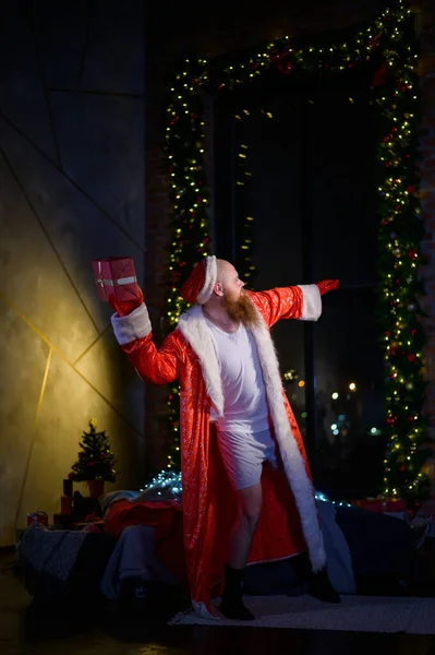 Papá Noel malo solo en Navidad. El hombre agresivo en el traje de Papá Noel en el fondo de las decoraciones de Año Nuevo . —  Fotos de Stock