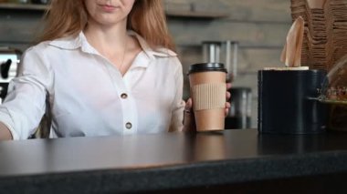 Bir kadın kredi kartıyla paket kahve alır. Çevrimiçi ödeme için terminal. Barista kahve satıyor..