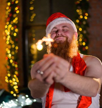 Noel Baba tatilde ışıldıyor. Noel Baba şapkalı kızıl sakallı bir adam yeni yılı kutluyor..