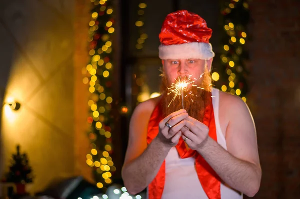 Санта с рождественскими блестками. Мужчина с рыжей бородой в шляпе Санта Клауса имитирует женщин. — стоковое фото
