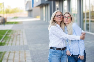 Gözlüklü güzel bir sarışın ve yaşlı annesi birlikte yürüyorlar. Anneler Günü. Güzel, yaşlı bir kadın yaşlı bir vatandaş ve onun yetişkin kızıdır. Farklı nesillerin mutlu kadınları..