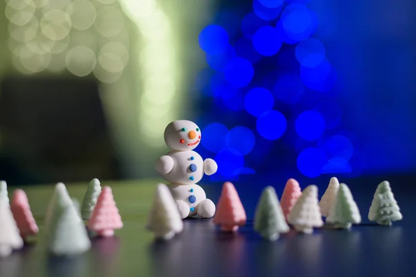 Bonhomme de neige mignon et petits arbres de Noël faits de guimauves sur le fond des lumières de Noël. Guirlande d'ampoules sur un arbre. Bonne année. — Photo