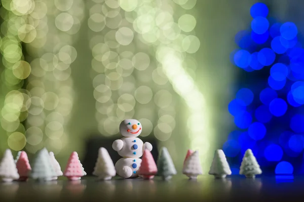 Bonhomme de neige mignon et petits arbres de Noël faits de guimauves sur le fond des lumières de Noël. Guirlande d'ampoules sur un arbre. Bonne année. — Photo