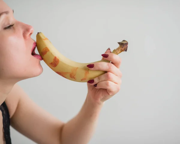 Primo piano del viso, labbra, lingua di una giovane ragazza europea che lecca una grande banana gialla e dolce . — Foto Stock