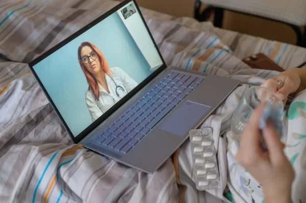 Μια ηλικιωμένη γυναίκα μιλάει με ένα γιατρό στο Skype. Μια συνταξιούχος πάσχει από αναπνευστική νόσο και φυσάει τη μύτη της. Ηλεκτρονική διαβούλευση. — Φωτογραφία Αρχείου