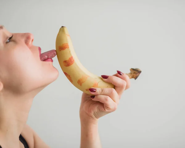 Primo piano del viso, labbra, lingua di una giovane ragazza europea che lecca una grande banana gialla e dolce . — Foto Stock