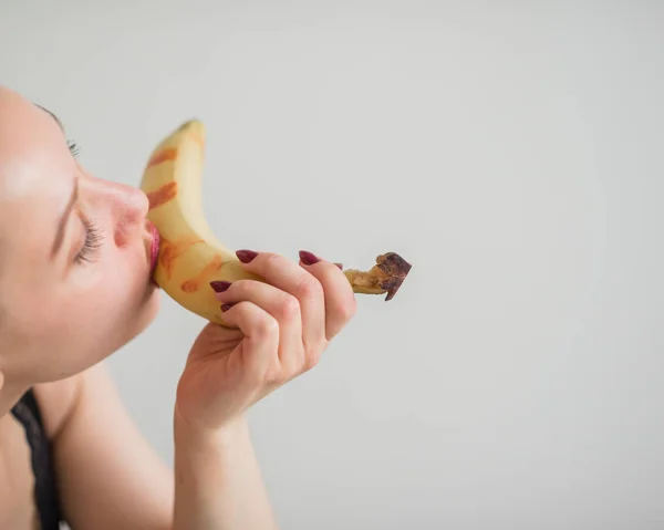 Primo piano del viso, labbra, lingua di una giovane ragazza europea che lecca una grande banana gialla e dolce . — Foto Stock