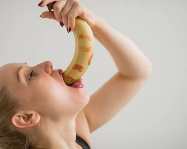 Adult European girl sexually licks and sucks a big banana. Fantasies about oral sex. Face close-up. — Stock Photo, Image