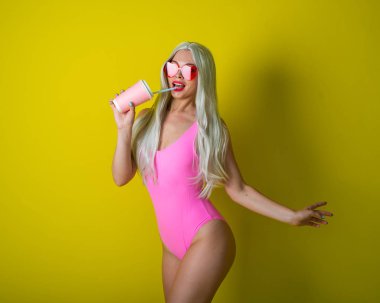 Pembe mayo giymiş koca popolu sarışın içki içiyor. Sarı arka planda poz veren peruklu bir kız. Kalpleri gören güneş gözlüklü, uzun yapay saçlı bir kadın..