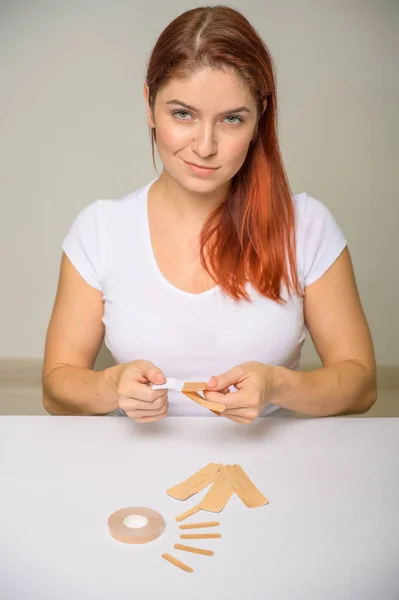 Retrato Hermosa pelirroja mujer con Kinesiología Cinta de lifting facial. Chica esteticista pone en la cara cinesio cinta para el lifting facial . — Foto de Stock