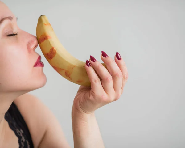 Vuxen europeisk flicka slickar sexuellt och suger en stor banan. Fantasier om oralsex. Ansikte närbild. — Stockfoto