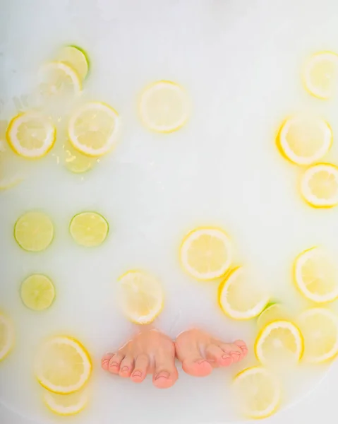 Девушка принимает молочную ванну с лимонами и лаймами. Fabrus spa. Уход за телом. Отбеливание кожи. Женские ноги . — стоковое фото