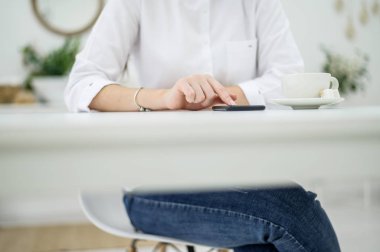 Beyaz gömlekli ve kot pantolonlu bir kadın bir kafede oturur ve kahve içer. Yemek molasında telefonda konuşan kadın bir ofis çalışanı. Restorandaki bir iş toplantısında müdür.