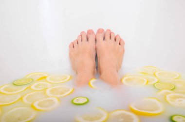 Kız limon ve limonla süt banyosu yapıyor. Citrus spa 'sı. Vücut bakımı. Cilt beyazlatıcı. Kadın bacakları..